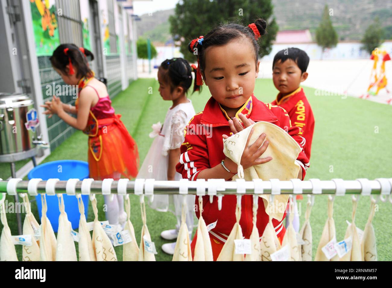 (170603) -- HUACHI, June 3, 2017 -- A little girl wipes with a towel after washing her hands at a kindergarten in Xinbao Village of Huachi County, northwest China s Gansu Province, June 3, 2017. To improve the hygiene education in remote areas, China Develpment Research Foundation and Unilever carried out a project to promote hand wash among children in classes. The project so far has covered more than 10,000 rural children in serveral provinces of China. ) (ry) CHINA-GANSU-HUACHI-RURAL KINDERGARTEN-EDUCATION (CN) ChenxBin PUBLICATIONxNOTxINxCHN   Huachi June 3 2017 a Little Girl wipes With a Stock Photo
