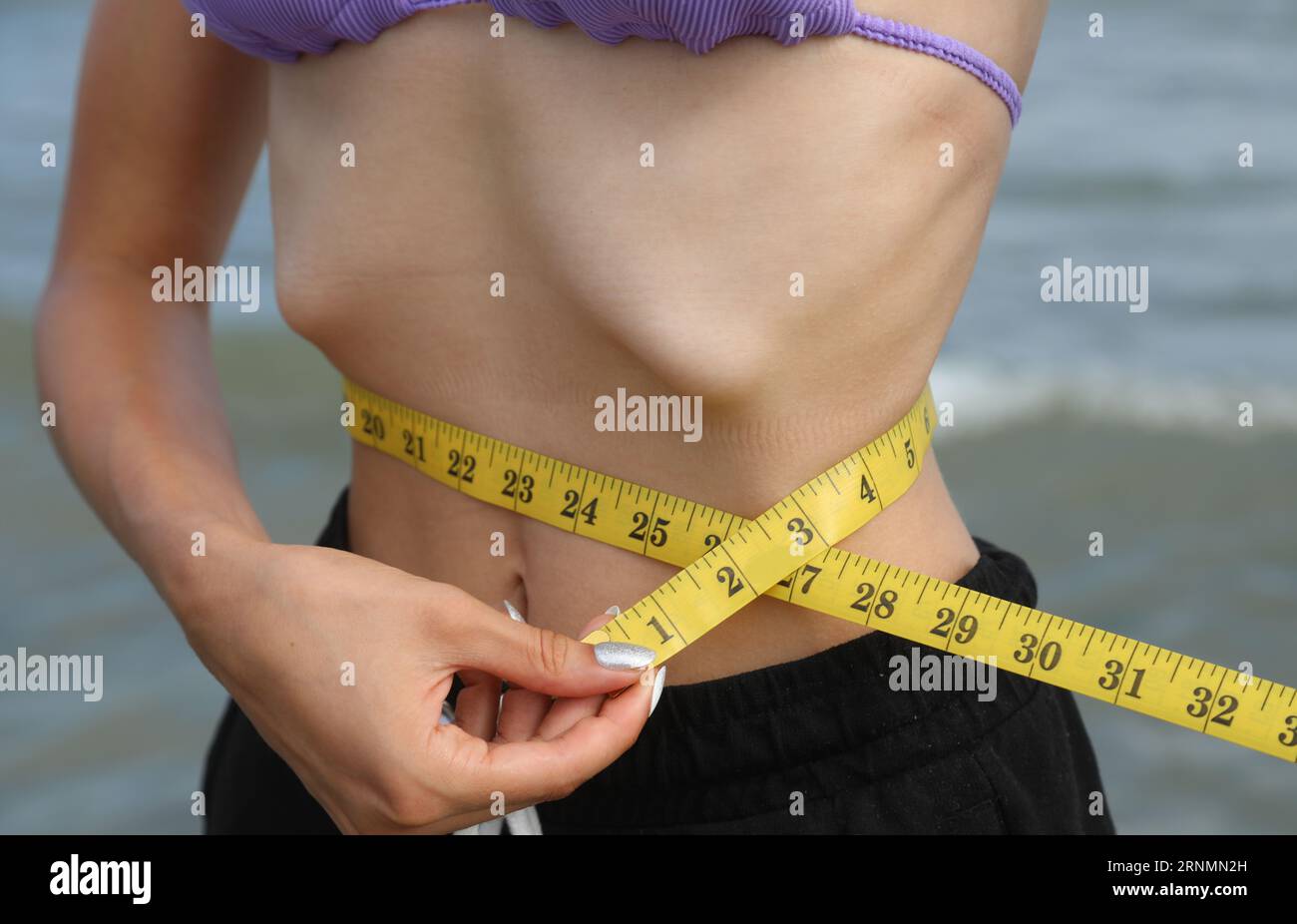 skinny young girl with eating disorder measuring ther waistline Stock Photo