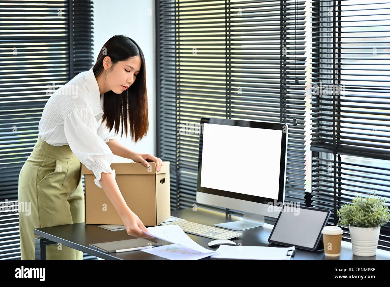 Frustrated female employee packing personal belongings in cardboard box ...