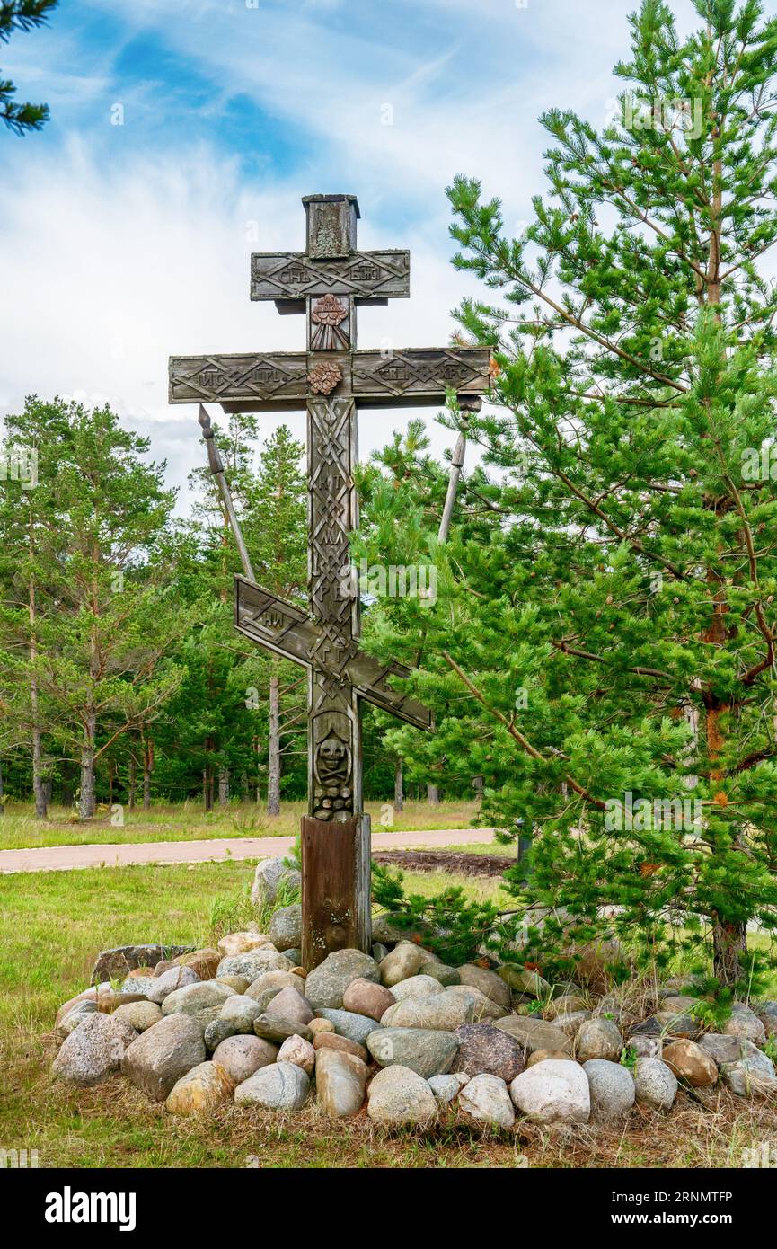 Old wooden cross on the island of Konevets on the shore of Lake Ladoga. The symbol of the monastic feat in a secluded monastery. Stock Photo