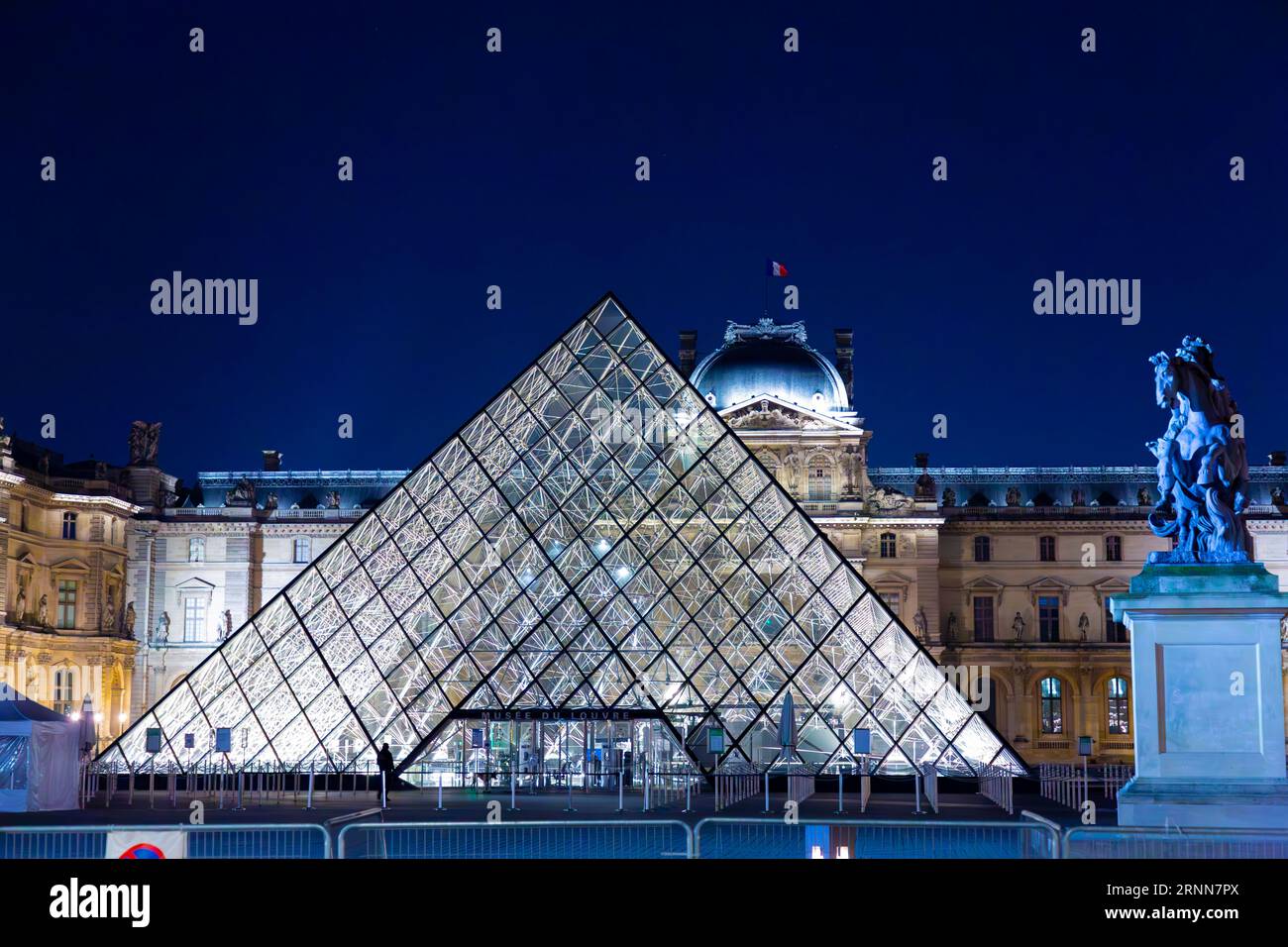 Paris, France - JAN 24, 2022: The glass pyramid of Louvre Museum, the main entrance to famous museum and gallery, completed in 1989. A beautiful winte Stock Photo