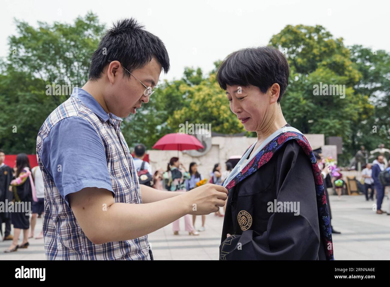 (170704) -- BEIJING, July 4, 2017 -- Gu Xiaoyi, an undergraduate of Peking University, helps his mother wear his baccalaureate gown, after the commencement and the degree ceremony of the 2017 undergraduates of the Peking University in Beijing, capital of China, July 4, 2017. ) (lb) CHINA-BEIJING-PKU-GRADUATION CEREMONY (CN) ShenxBohan PUBLICATIONxNOTxINxCHN   Beijing July 4 2017 GU Xiaoyi to UNDERGRADUATE of Beijing University Helps His Mother Wear His Baccalaureate Gown After The commencement and The Degree Ceremony of The 2017 undergraduates of The Beijing University in Beijing Capital of Ch Stock Photo