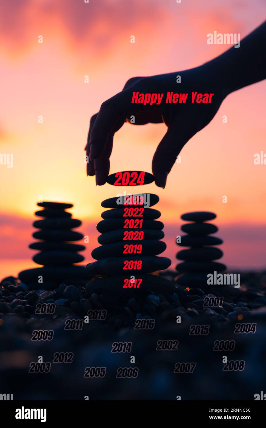Vertical İmage of pyramid of pebbles on the beach at sunset. Concept of the zen and happy new year 2024, stability, harmony, balance and meditation, Stock Photo