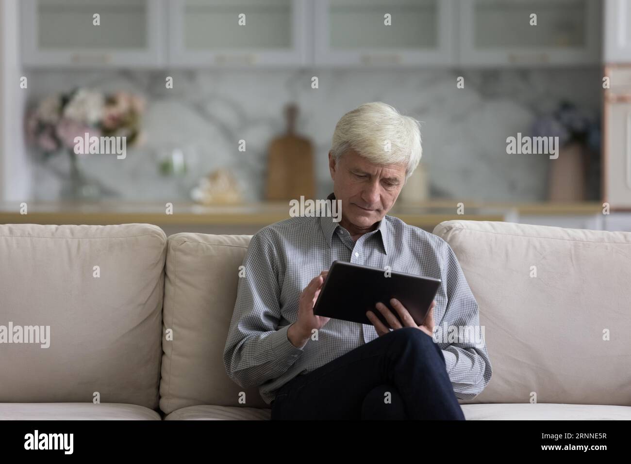 Serious Caucasian older retired man using tablet computer Stock Photo