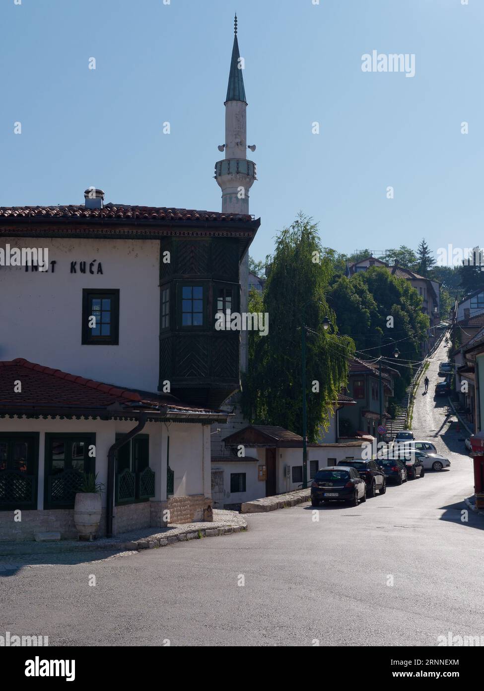 Inat Kuca restaurant with Minaret and steep road behind in the city of Sarajevo, Bosnia and Herzegovina, September 02, 2023 Stock Photo