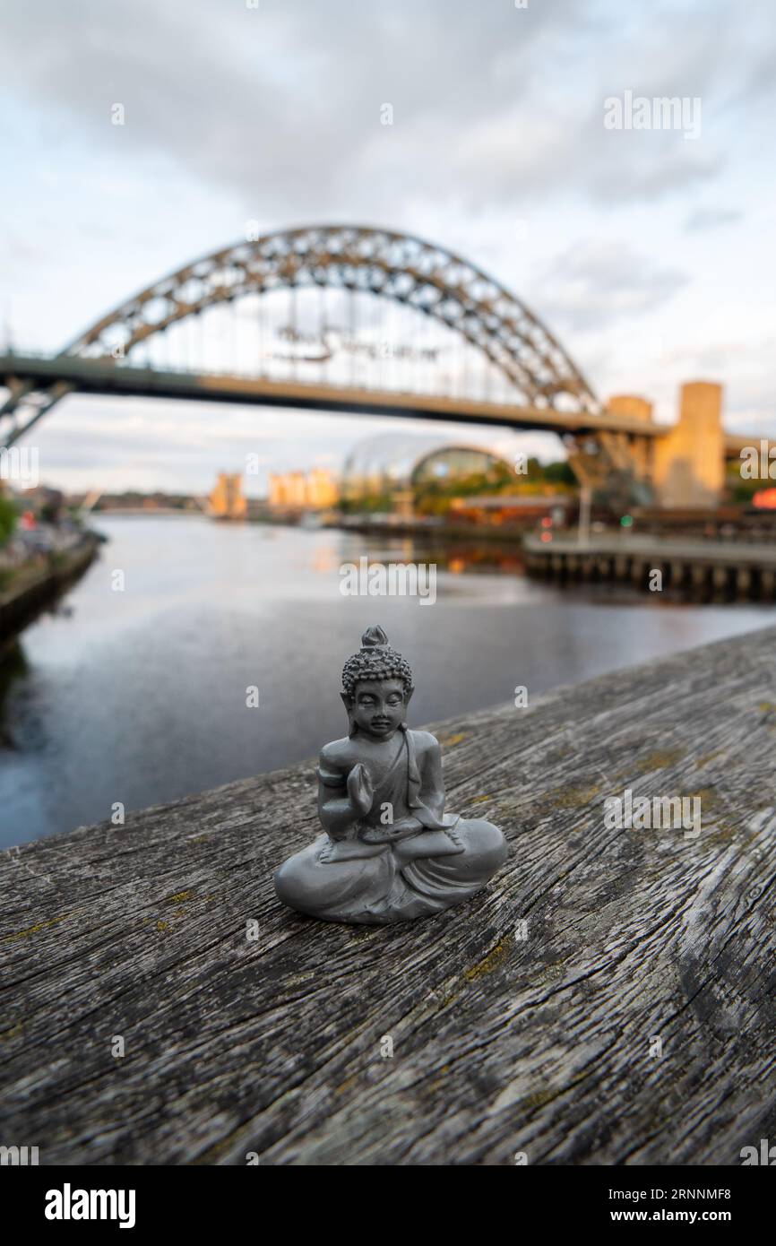 Figure in lotus position with River Tyne cityscape background in Newcastle upon Tyne, UK, Concept of urban meditation, yoga in the city. Stock Photo