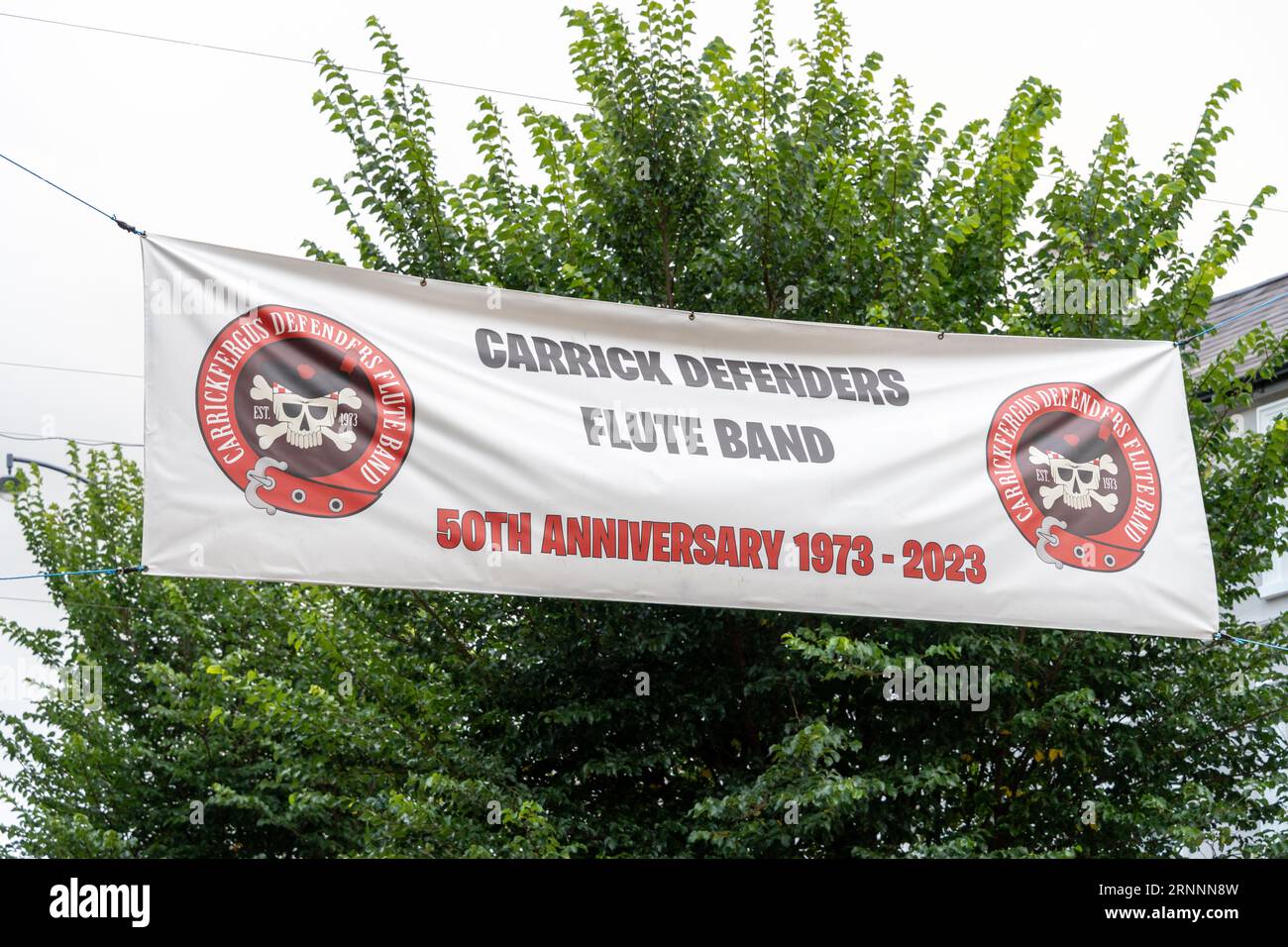 A banner hung across the street in Carrickfergus, northern Ireland advertises the 50th anniversary of the Carrickfergus Defenders Flute Band Stock Photo