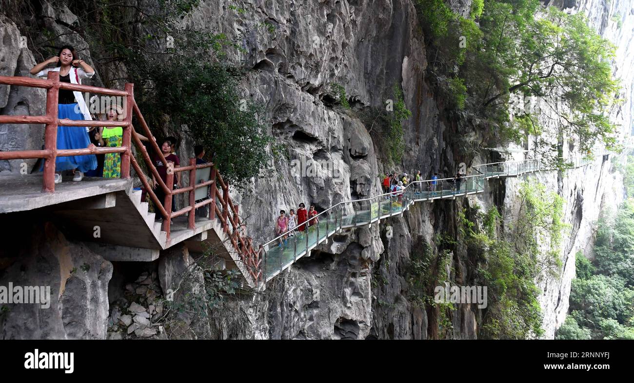 Tourists walk on a glass-made plank road built along a cliff at
