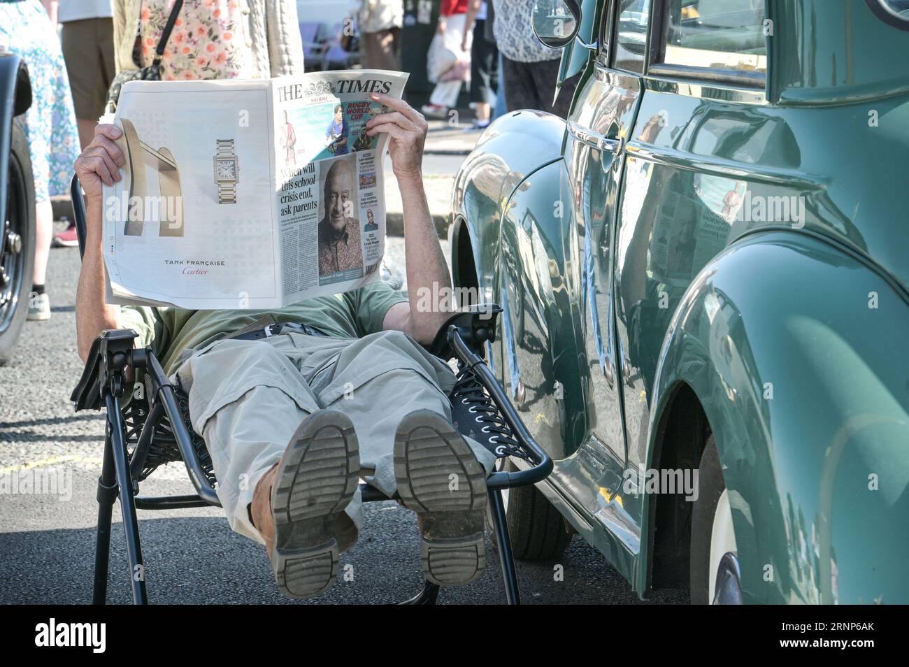 Morecambe, Lancashire - September 2nd 2023 - Visitors enjoyed Morecambe's Vintage By The Sea festival on Saturday. Many of whom came dressed in vintage clothing and soaked up the atmosphere. A man took a rest in the shade of his vintage car reading a newspaper as the blaring sun beated down. Credit: Stop Press Media/Alamy Live News Stock Photo