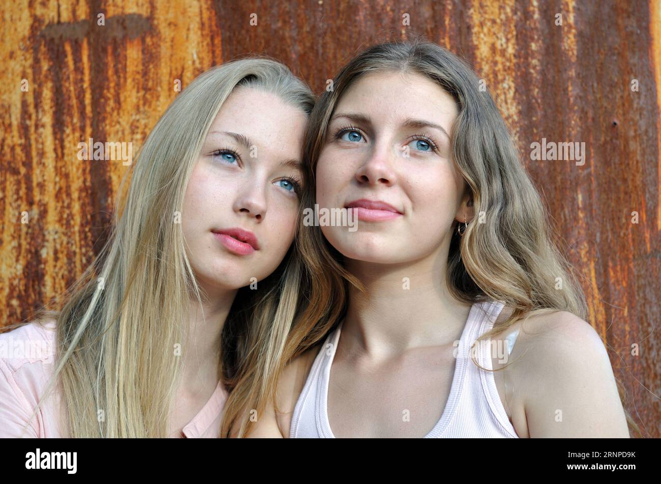 portrait of two tired girls with  blue eyes on rusty background in summer day Stock Photo