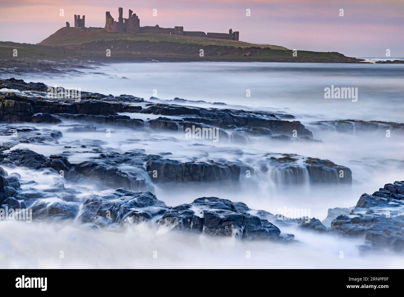 Dunstanburgh Castle from queen margarets cove, near Craster, Northumberland, UK Stock Photo