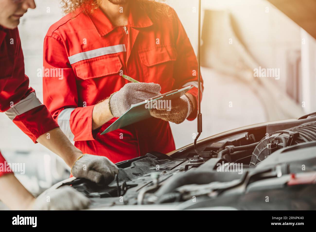 mechanic team check list engine repair maintenance oil liquid change at front hood of old car in auto service workshop Stock Photo
