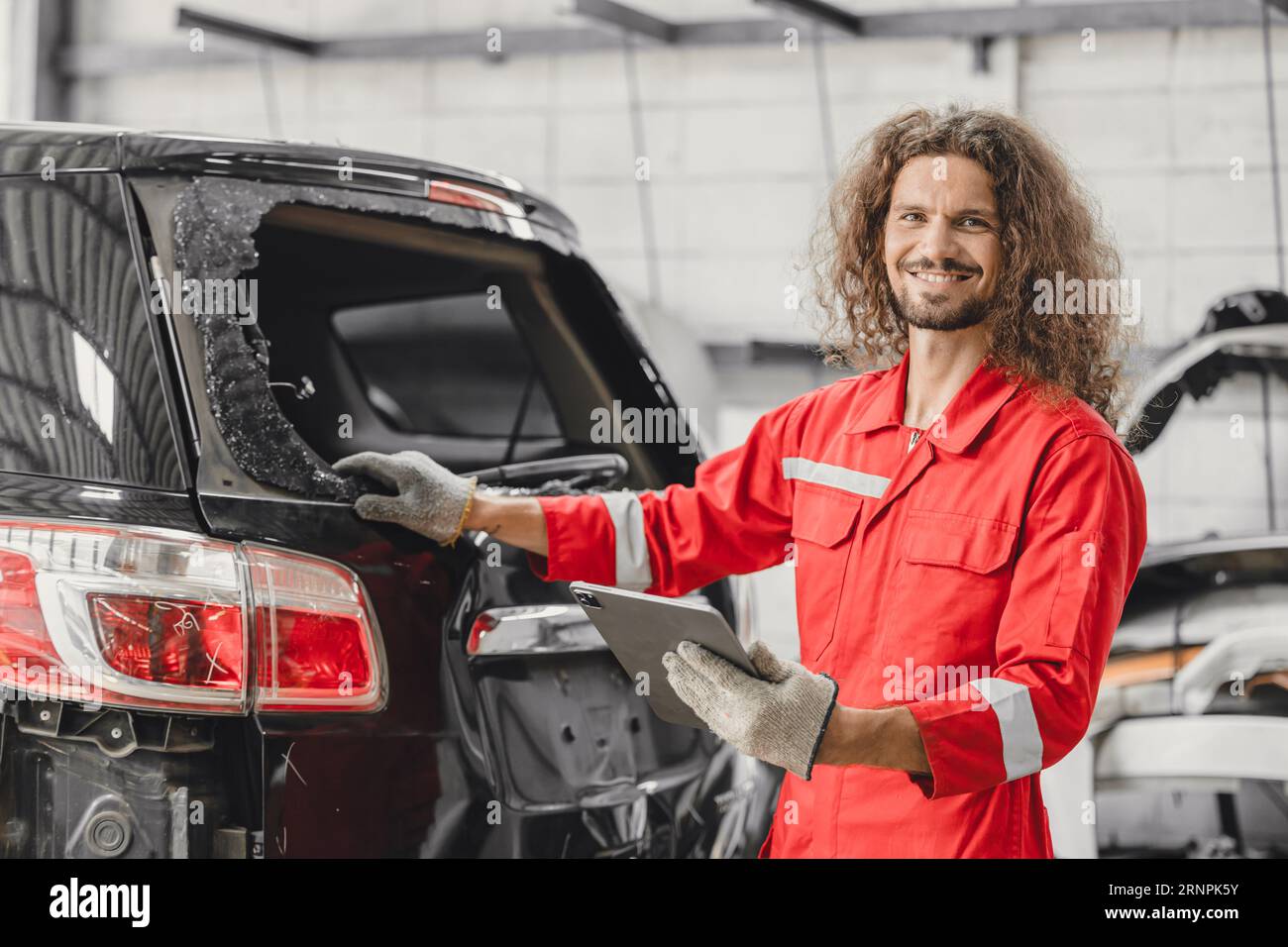 mechanic male happy smiling work insurance online claim accident car in garage auto workshop from internet tablet Stock Photo