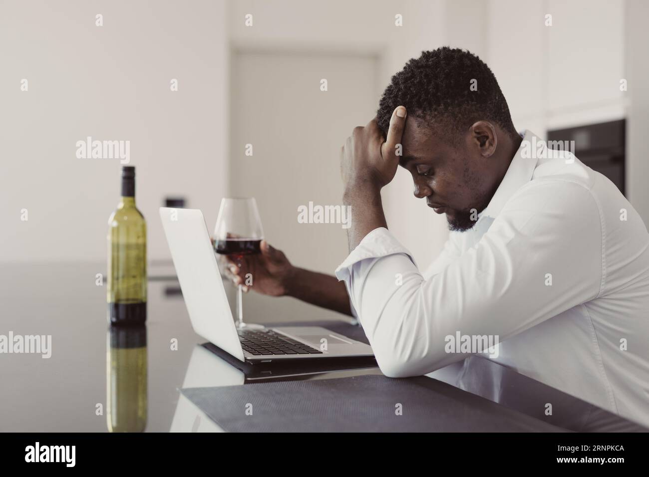 Black businessman depressed stressed from life problems and business fail drink alcohol front laptop computer alone at home Stock Photo