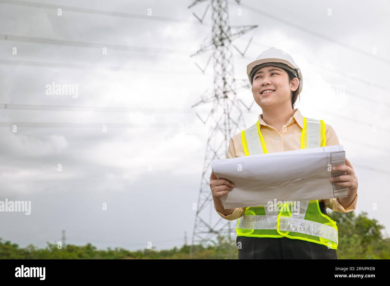 Happy engineer woman happy smiling with high voltages electricity transmission pole building project on background Stock Photo