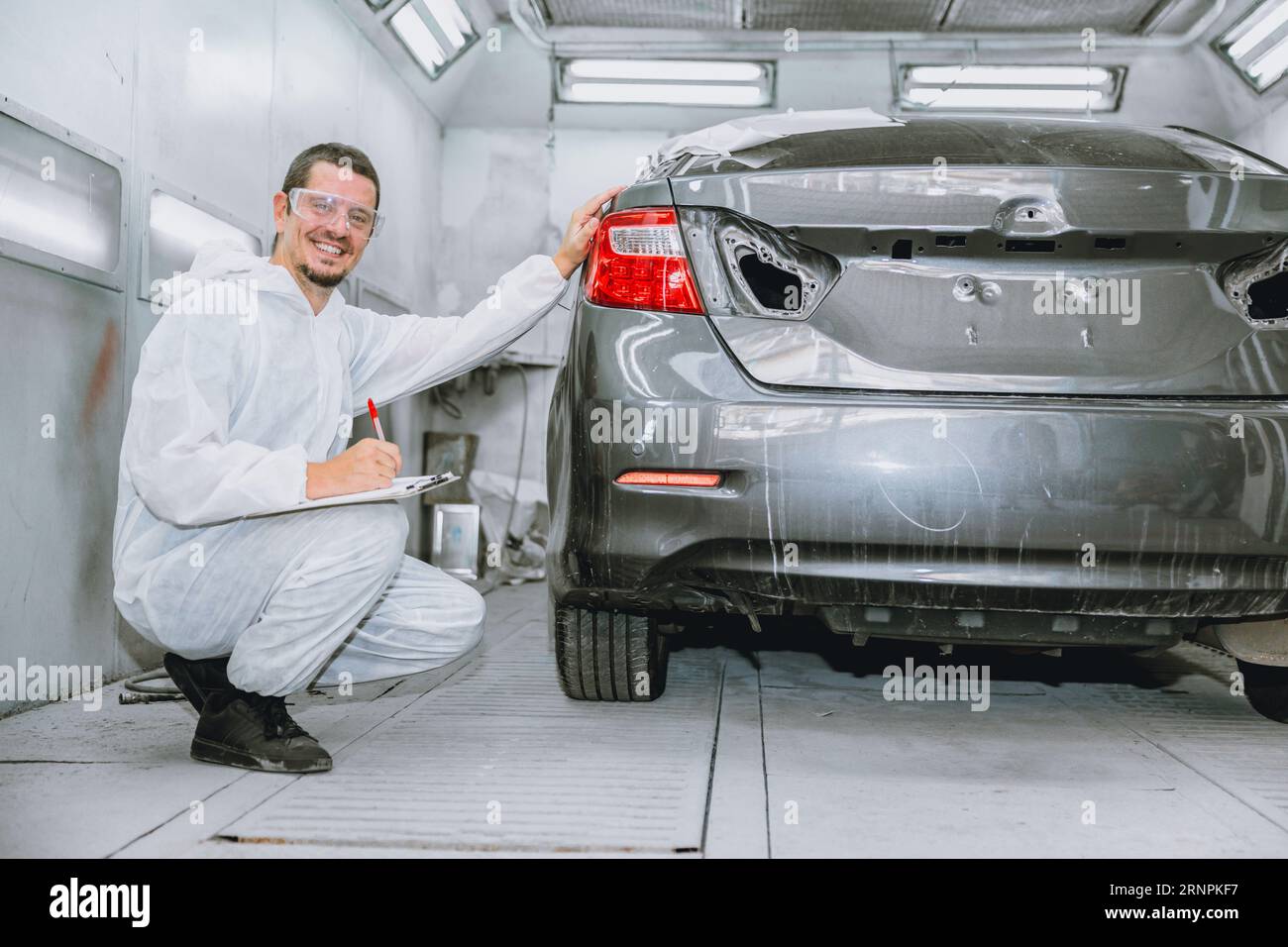 car body painter professional male worker checking color paint detail in auto garage bodywork