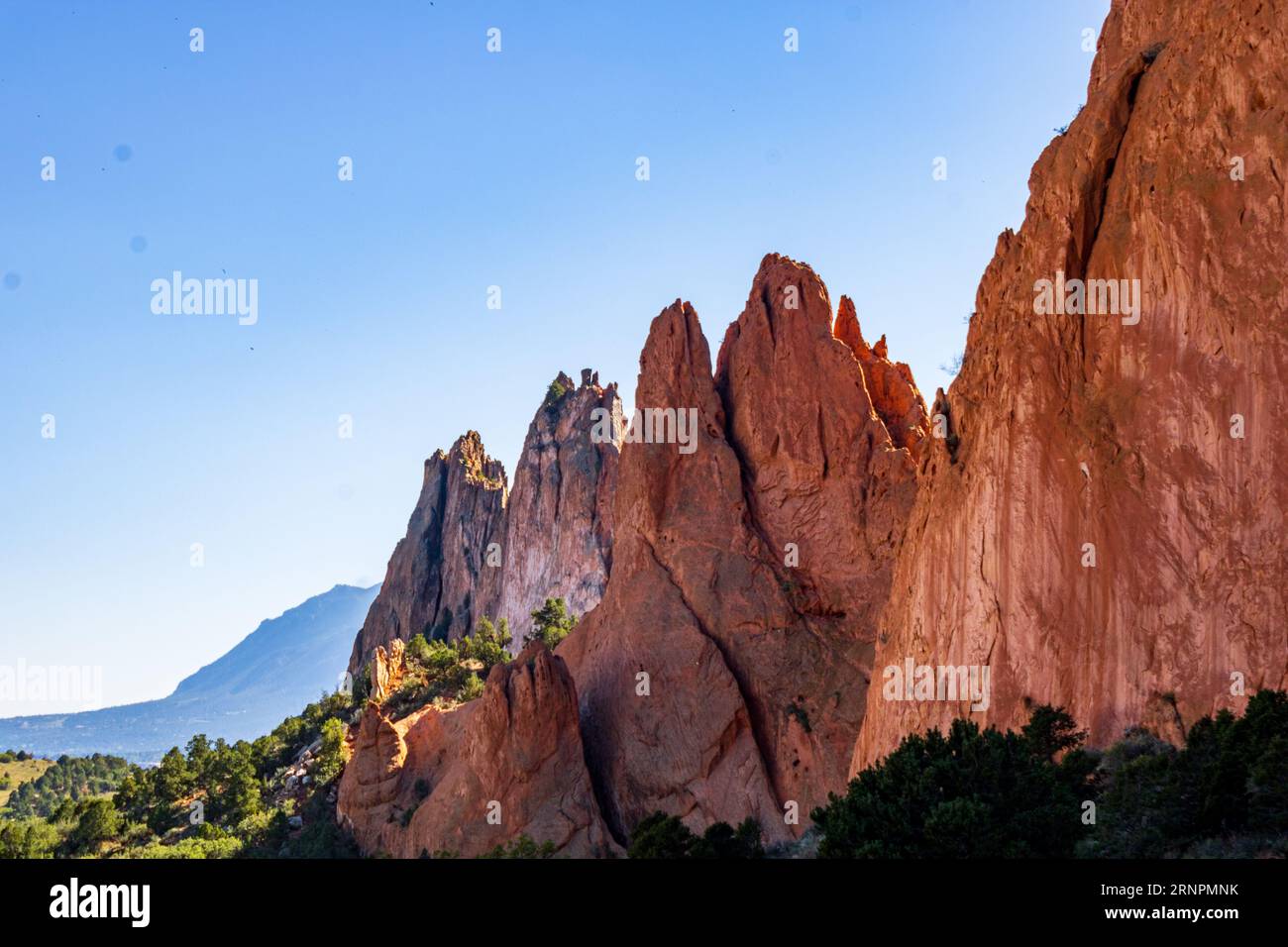 Aerial shot of a stunning desert canyon in Colorado's Garden of the Gods, featuring vibrant red and orange rock formations set against a backdrop of b Stock Photo