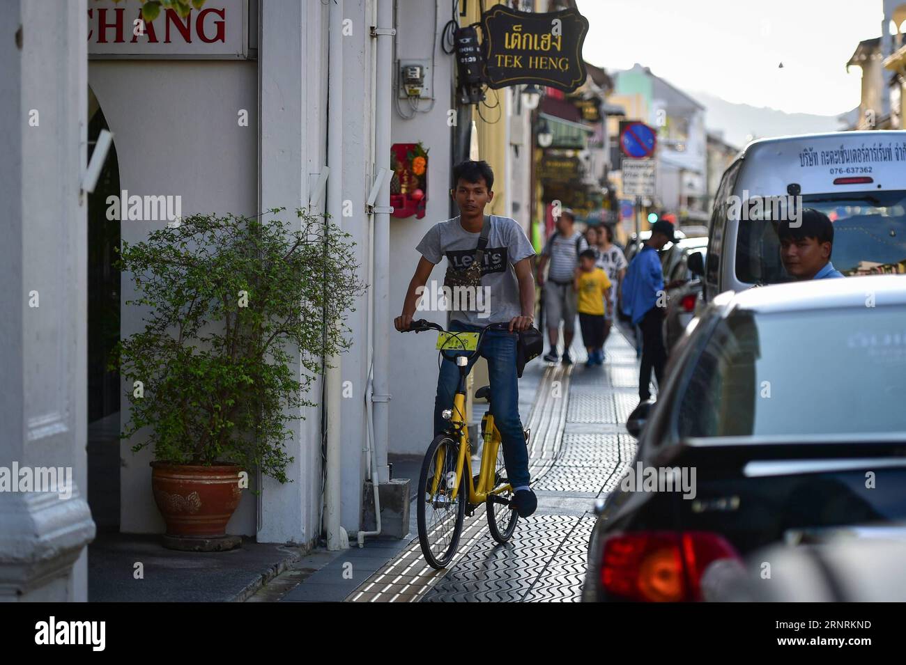 (171007) -- PHUKET, Oct. 7, 2017 -- A man rides an ofo sharing-bike at a commercial area in Phuket, Thailand, Oct. 5, 2017. China s dock-less bike-sharing company ofo provided more than 1,000 bikes in Phuket s key locations in late September and offered a 1-month free trial without deposit fee. Now the bike-sharing service has benefited local residents and tourists. Ofo s regular service fee will be charged at 5 Baht per 30 minutes usage, with a deposit fee of 99 Baht. )(zhf) THAILAND-PHUKET-CHINA-BIKE-SHARING-OFO LixMangmang PUBLICATIONxNOTxINxCHN Stock Photo