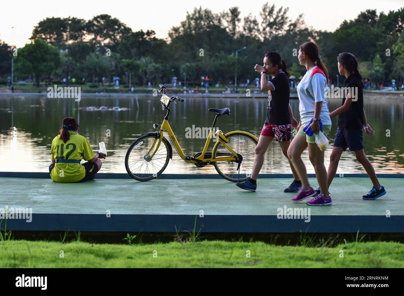 (171007) -- PHUKET, Oct. 7, 2017 -- People walk past an ofo sharing-bike at a public park in Phuket, Thailand, Oct. 5, 2017. China s dock-less bike-sharing company ofo provided more than 1,000 bikes in Phuket s key locations in late September and offered a 1-month free trial without deposit fee. Now the bike-sharing service has benefited local residents and tourists. Ofo s regular service fee will be charged at 5 Baht per 30 minutes usage, with a deposit fee of 99 Baht. )(zhf) THAILAND-PHUKET-CHINA-BIKE-SHARING-OFO LixMangmang PUBLICATIONxNOTxINxCHN Stock Photo