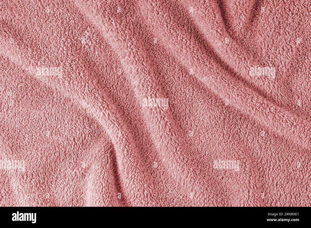 Terry cloth, red towel texture background. Wrinkled and crumped soft fluffy textile bath or beach towel material. Top view, close up. Stock Photo