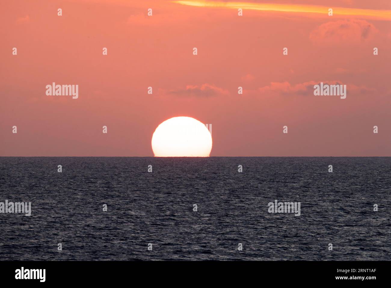 Sunset on the English Channel, sun sinking into the sea under a red, slightly cloudy sky, Portbail, Cotentin, Manche, Normandy, France Stock Photo
