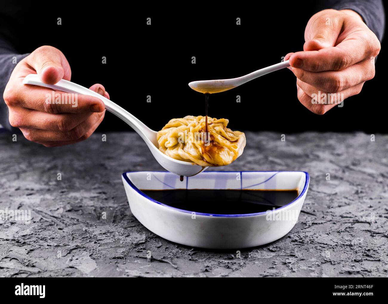Hands pouring sauce dumpling front view Stock Photo