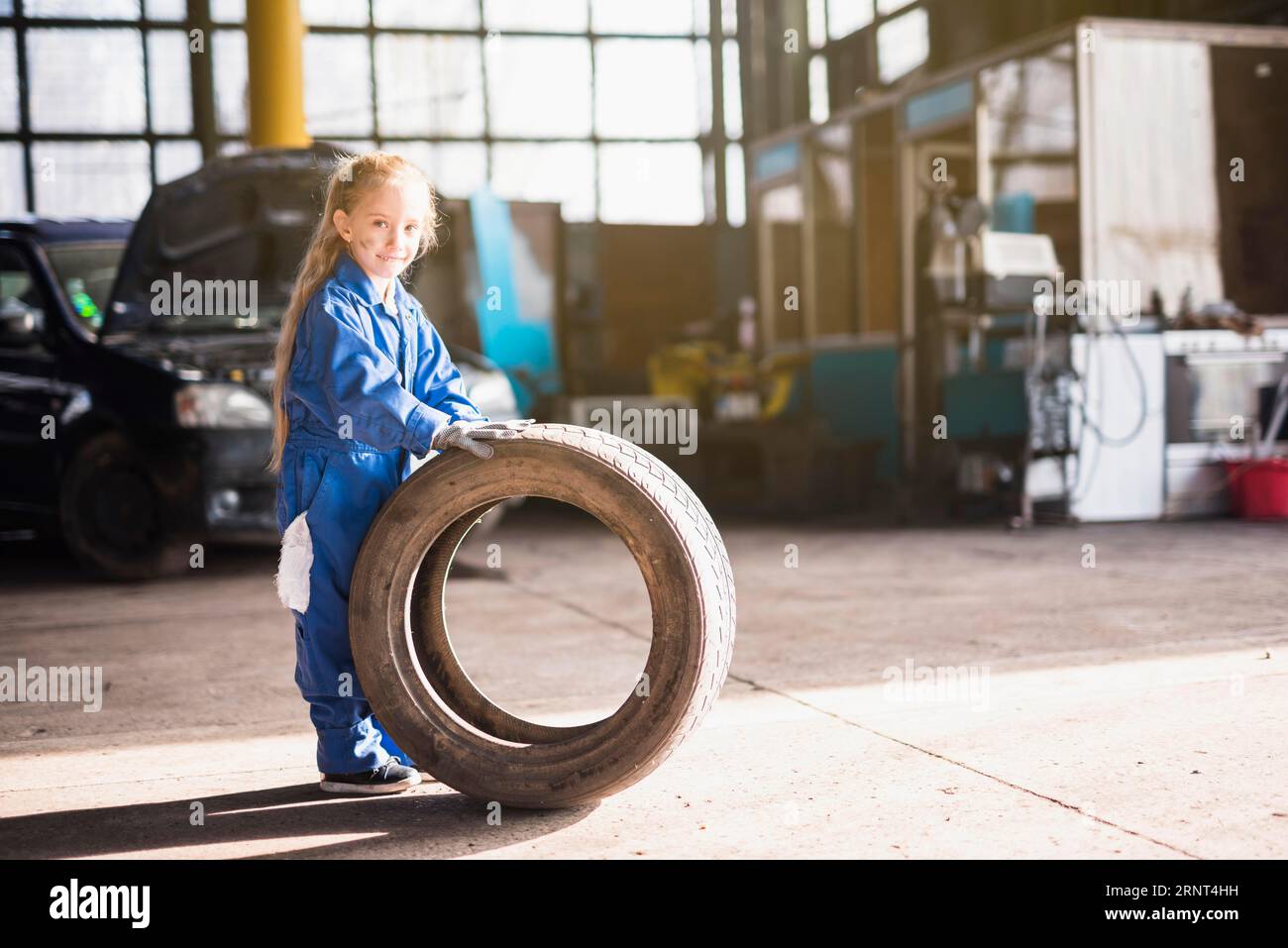 Little girl overall standing with car wheel Stock Photo