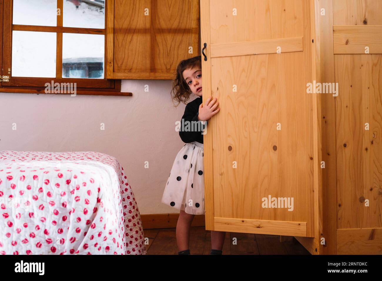 Cute girl peeking from wooden cupboard Stock Photo
