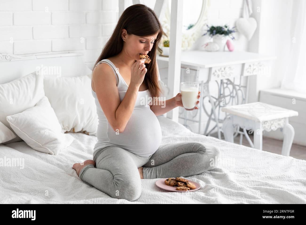 Pregnant woman eating chocolate cookies drinking milk Stock Photo