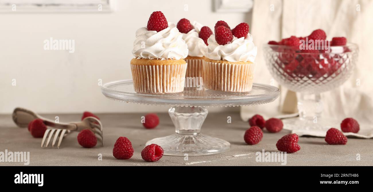 Stand with tasty raspberry cupcakes on table Stock Photo