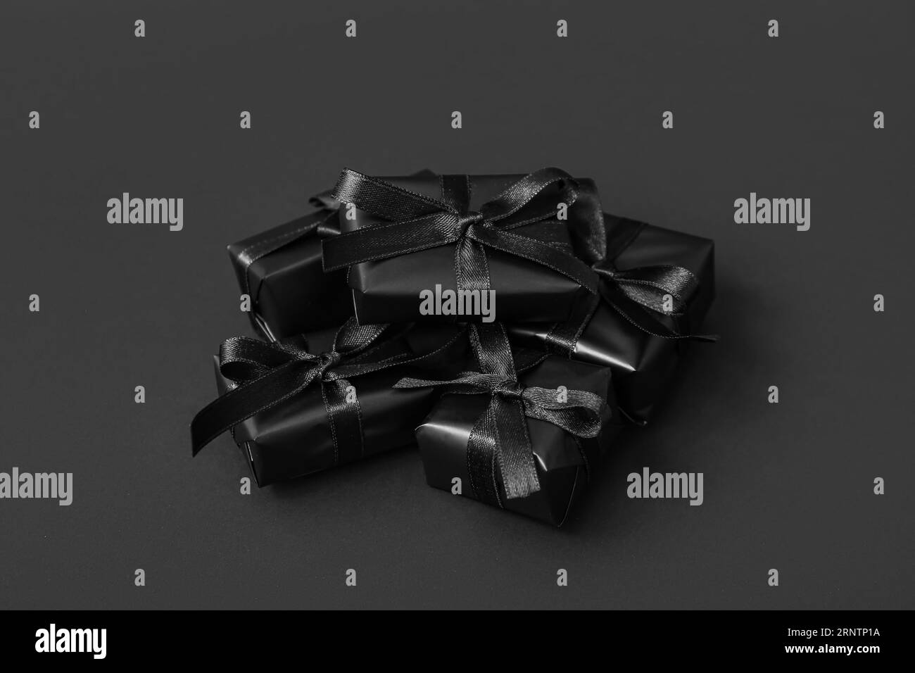 Gift boxes with ribbons on black background, closeup. Black Friday