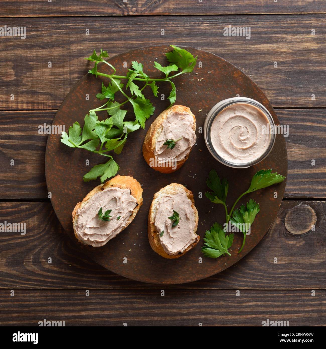 Toasted bread with chicken liver pate on cutting board over wooden background. Top view, flat lay Stock Photo