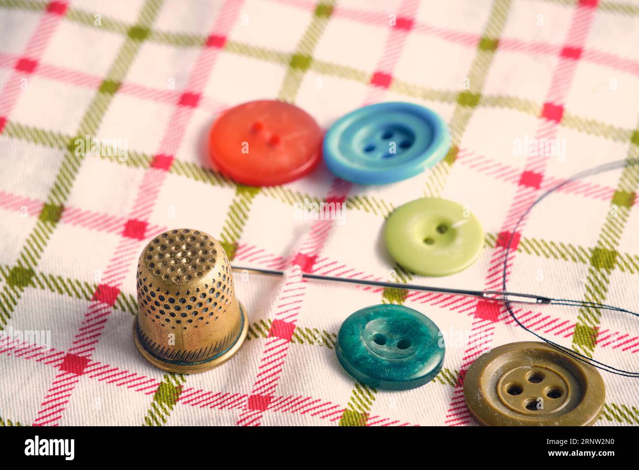 Sewing kit consisting needle, thimble and buttons fabric background Stock Photo