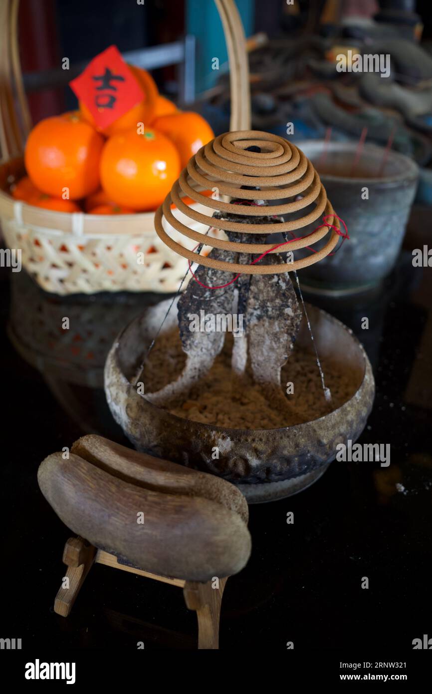 Incense sticks and divination blocks on a table of a shrine in Taiwan. The red paper on top is a Chinese character which means auspicious. Stock Photo
