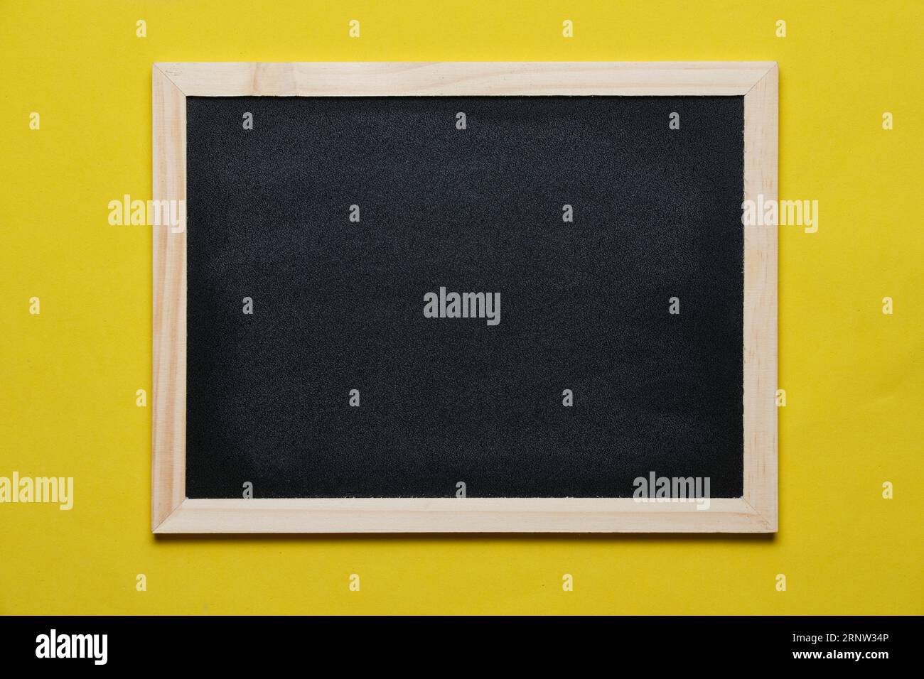 Black blackboard for notes in wooden frame yellow background Stock Photo