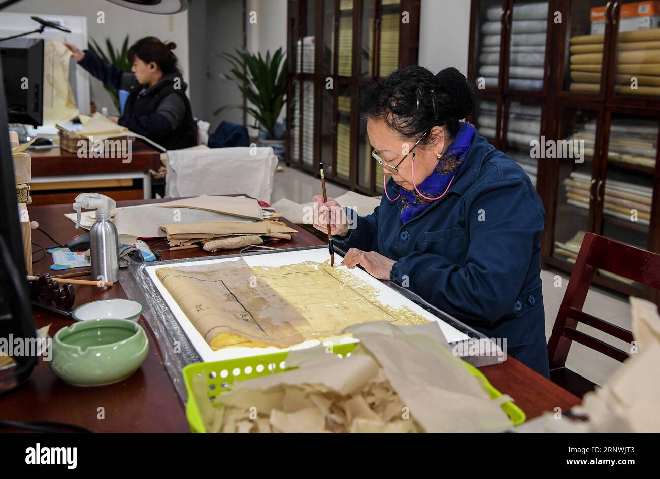 (171222) -- CHENGDU, Dec. 22, 2017 -- Yuan Dongjue repairs one page of a book over 180 years, in Sichuan Provincial Library in Chengdu, capital of southwest China s Sichuan Province, Dec. 21, 2017. Yuan Dongjue, a 70-year-old expert of ancient books repairs, has kept working on ancient book repair and conservation since 1983 in Ancient Books Repair Center of Sichuan Provincial Library. In her 34 years career time, Yuan has repaired about 200 valuable ancient Chinese books, some of them could date back to 1,000 years ago. The repair work consists of over 10 different steps. To repair only one p Stock Photo