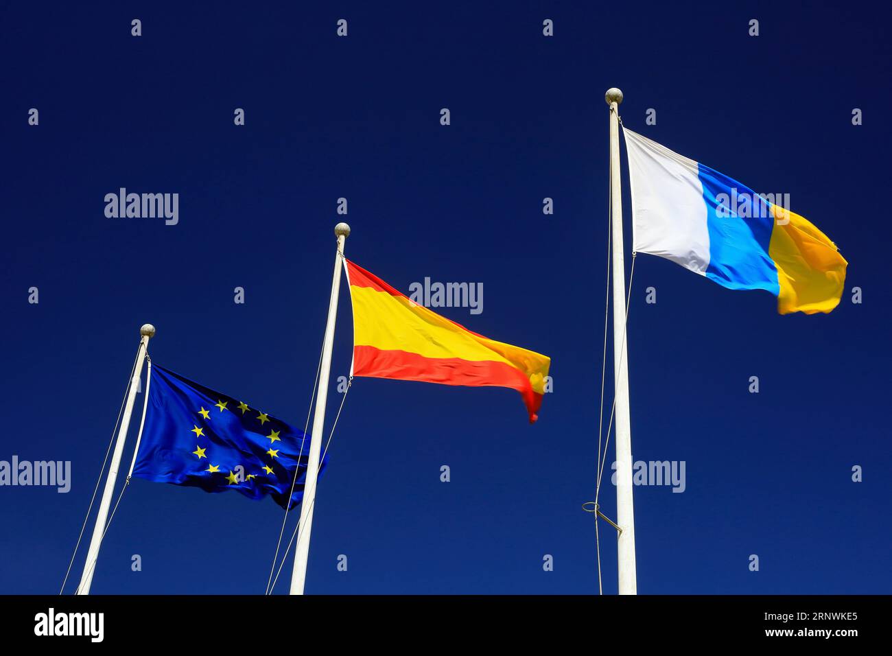 Three flags against blue sky, Lanzarote Taken February 2023. From left - European Union flag, Spanish Flag and Canarian Flag. Stock Photo
