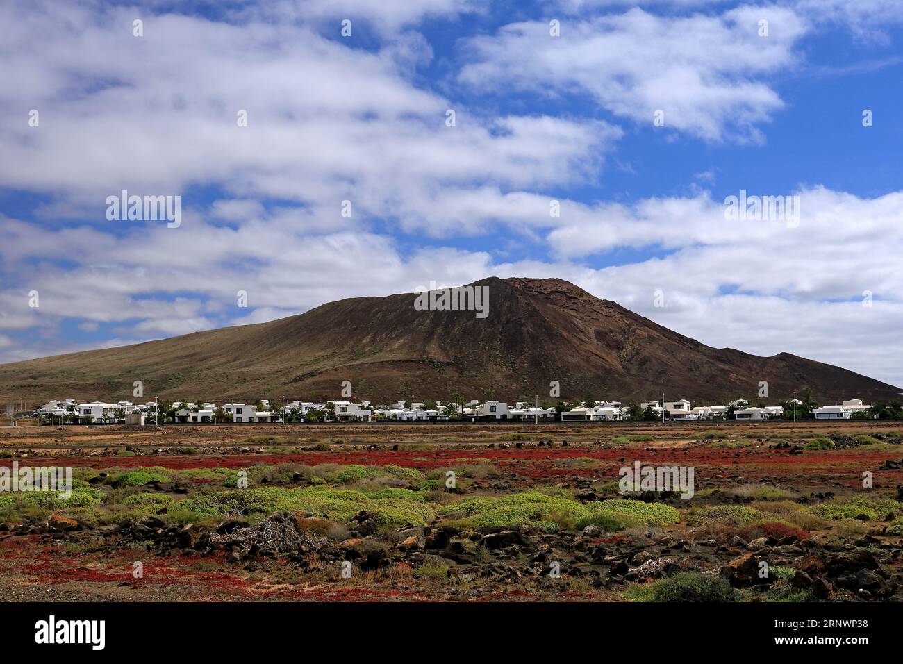 Colourful scenery and Montana Roja (Red Mountain) inactive volcano with small village at its base. Playa Blanca, Lanzarote, Canary Islands, Spain. Stock Photo