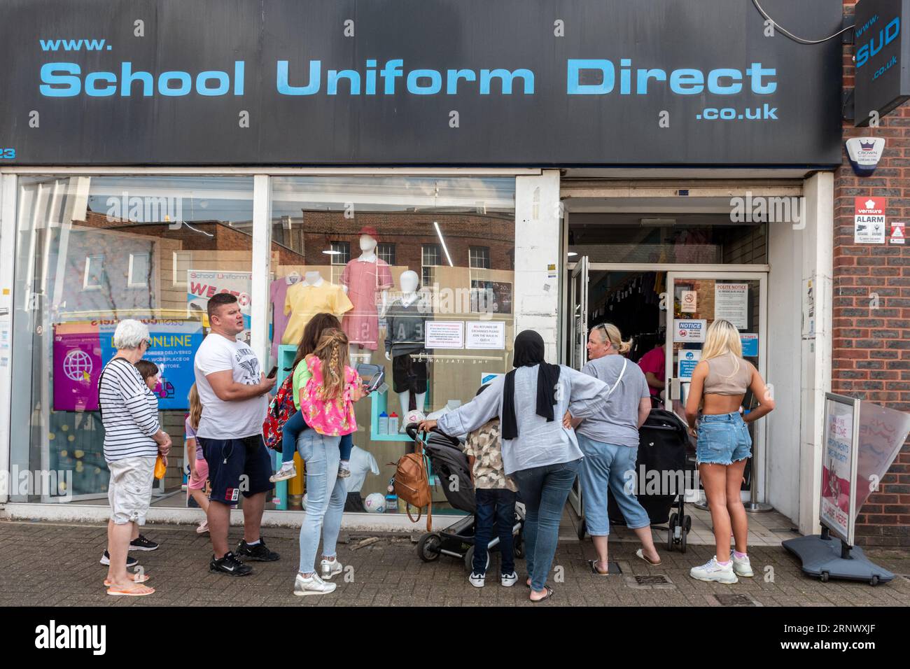 People buying school uniforms. September 2nd 2023. People queue outside a School Uniform Direct shop in Staines-upon-Thames in Surrey, England, UK, waiting to buy school uniform a few days before children go back to school for the new term. The high cost of school uniforms is causing difficulties to some families during the cost of living crisis. Stock Photo