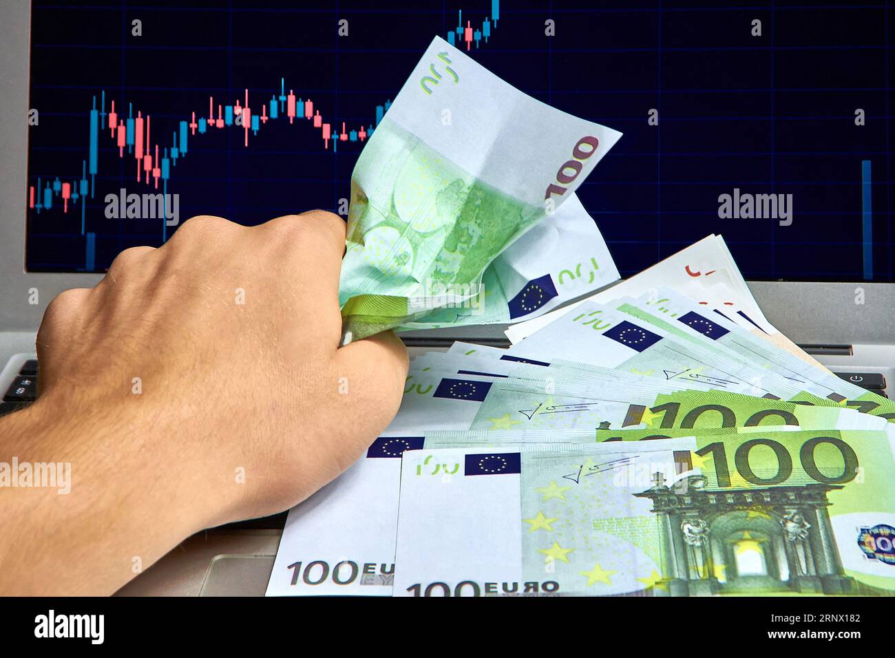 Paper bills clenched in a fist, against a stock market chart Stock