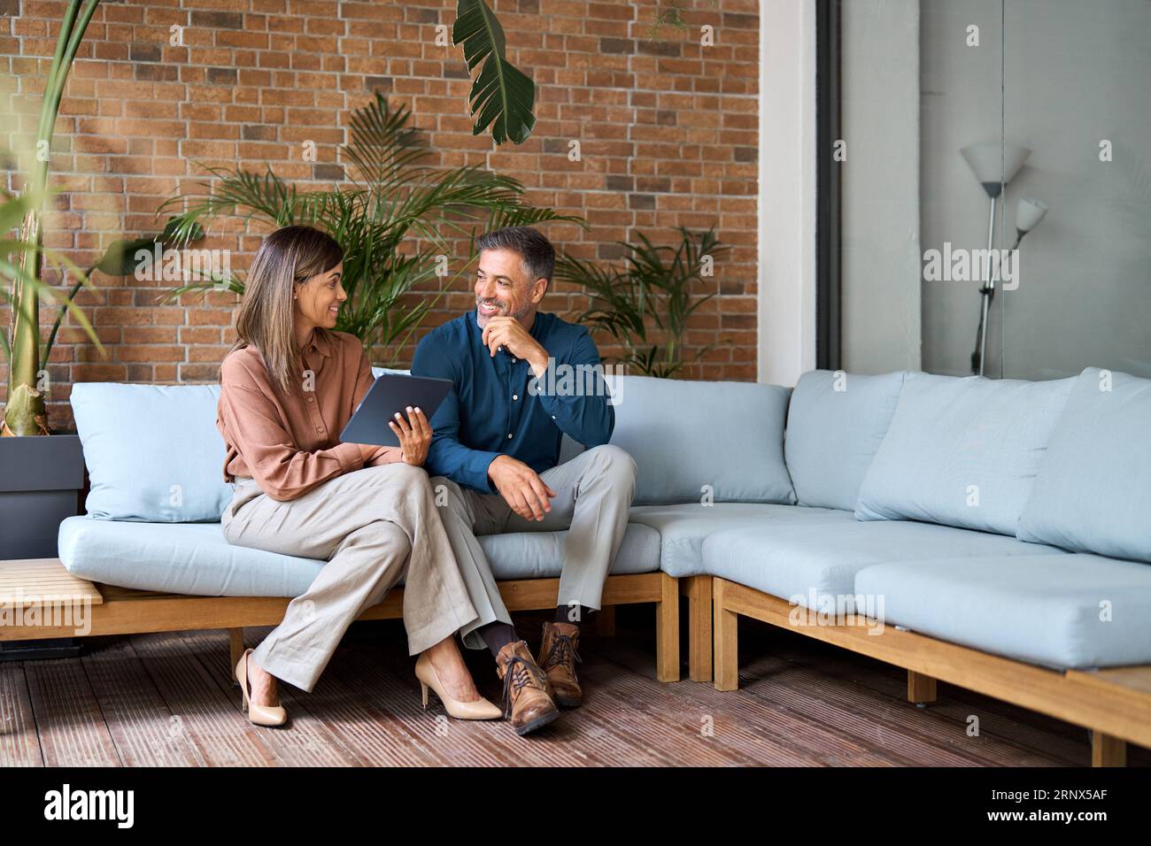 Two happy professional business executives talking using tablet in office. Stock Photo