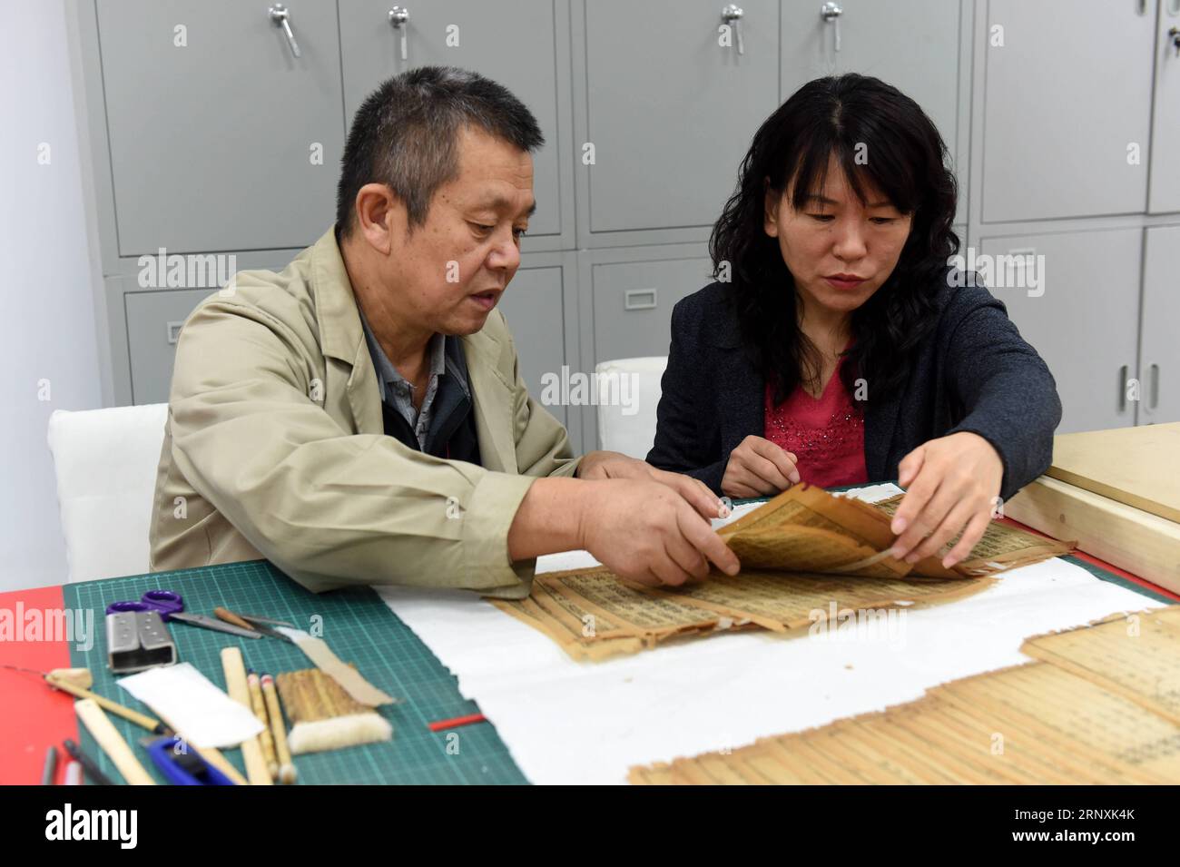 (180202) -- SHIJIAZHUANG, Feb. 2, 2018 -- Su Wenzhu (R) repairs ancient books with her colleague at the Hebei Library in Shijiazhuang, capital of north China s Hebei Province, Nov. 21, 2017. Su Wenzhu, a delegate to the 19th National Congress of the Communist Party of China (CPC), is director of the special collection department in Hebei Library. She is dedicated to protecting ancient books and digging out traditional Chinese cultural heritages within them, in an aim to strengthen Chinese people s cultural confidence and publicize the traditional Chinese culture. ) (zwx) CHINA-HEBEI-SU WENZHU- Stock Photo