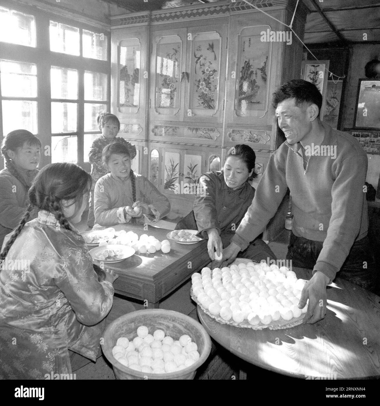 (180207) -- BEIJING, Feb. 7, 2018 -- File photo taken in February, 1980 shows a family cooking niandoubao , a kind of steamed bun stuffed with sweetened bean paste, in Hailun County, northeast China s Heilongjiang Province. According to traditional cultural elements and customs, some indispensable dishes carrying symbolic meanings are served during the Spring Festival. They are ceremonious processes and sweet memories for those who live and work away from home. Spring Festival, or better known as Chinese Lunar New Year, is the most important festival for all Chinese, which has a history of mor Stock Photo