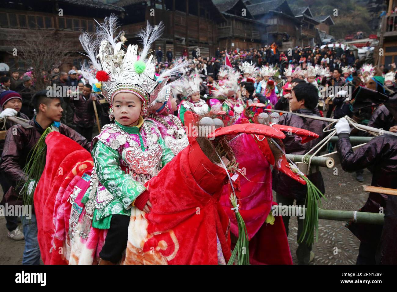 (180223) -- LIPING, Feb. 23, 2016 -- Participants carry children in traditional custumes on sedan chairs to march around the village as they sing and dance to pray for good fortune and a good harvest year during a performance to celebrate the traditional Dong ethnic group s festival Tai Guan Ren, in Huanggang Village of Liping County, Qiandongnan Miao and Dong Autonomous Prefecture, southwest China s Guizhou Province, Feb. 22, 2018. Tai Guan Ren, which means carry the peace and luck envoy, is an annual Dong people s festival usually celebrated during the beginning of the Chinese Lunar New Year Stock Photo