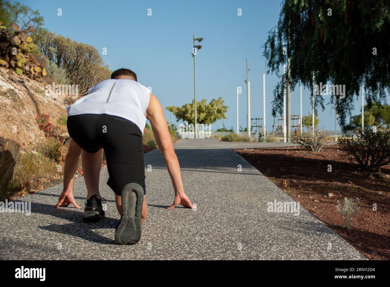 Young Caucasian man simulating the start on the marks of an athletics race. Copy space on the right Stock Photo
