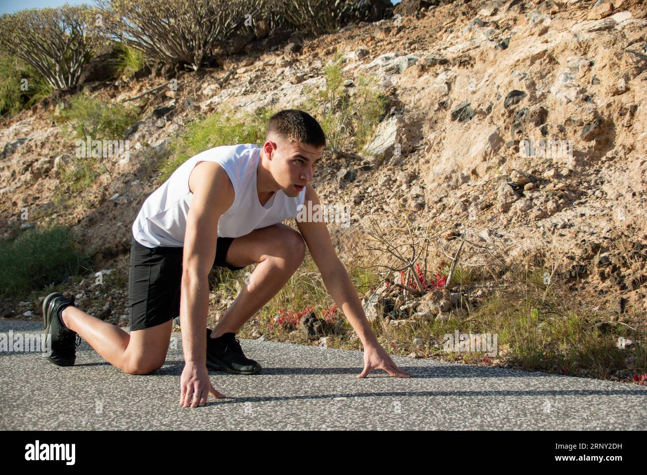 Close-up of a concentrated young Caucasian man simulating the start of an athletics race Stock Photo