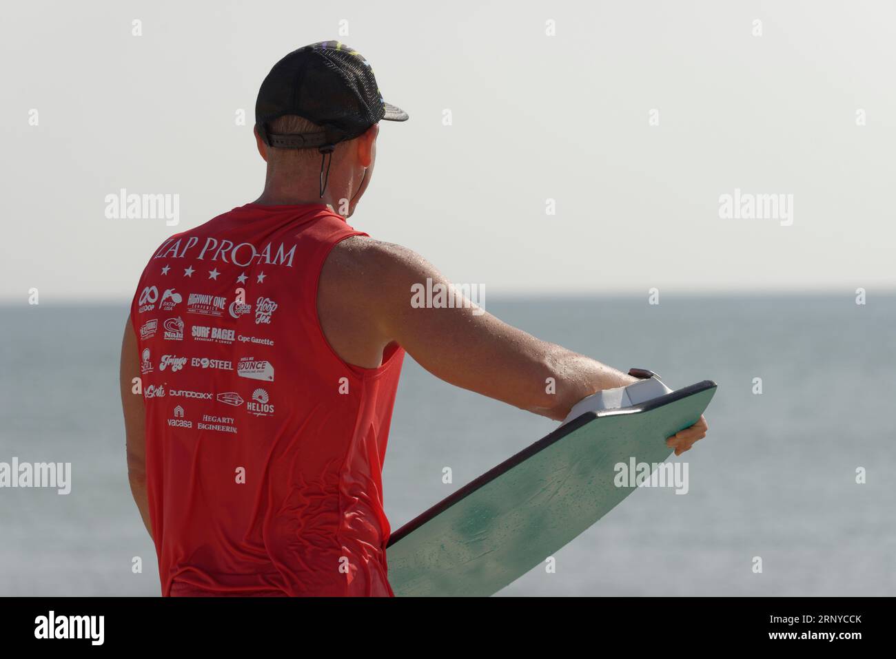 Male contestant waits for the next wave at the Zap Pro/Am Championships of Skimboarding, August 11, 2023, Dewey Beach, Delaware USA. Stock Photo