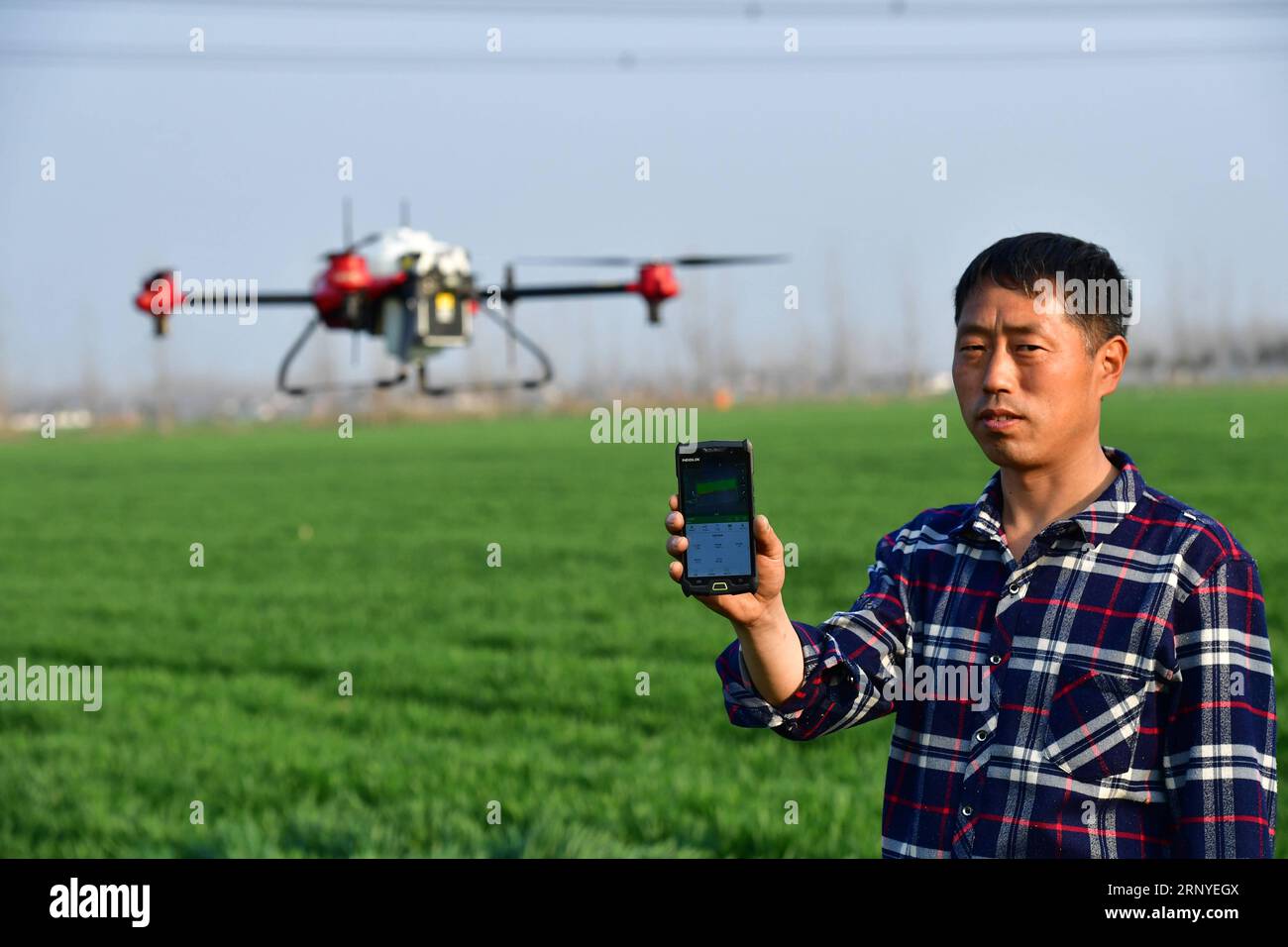 (180315) -- ZHENGZHOU, March 15, 2018 -- Technician Xu Wei takes a mobile phone to direct a drone to spray pesticide in the field at Daxing Village of Zhumadian City, central China s Henan Province, March 13, 2018. Drones, electric watering machines and other intelligent equipments have started to serve the farming industry. ) (ry) CHINA-HENAN-FARM WORK-INTELLIGENT DEVICES (CN) FengxDapeng PUBLICATIONxNOTxINxCHN Stock Photo