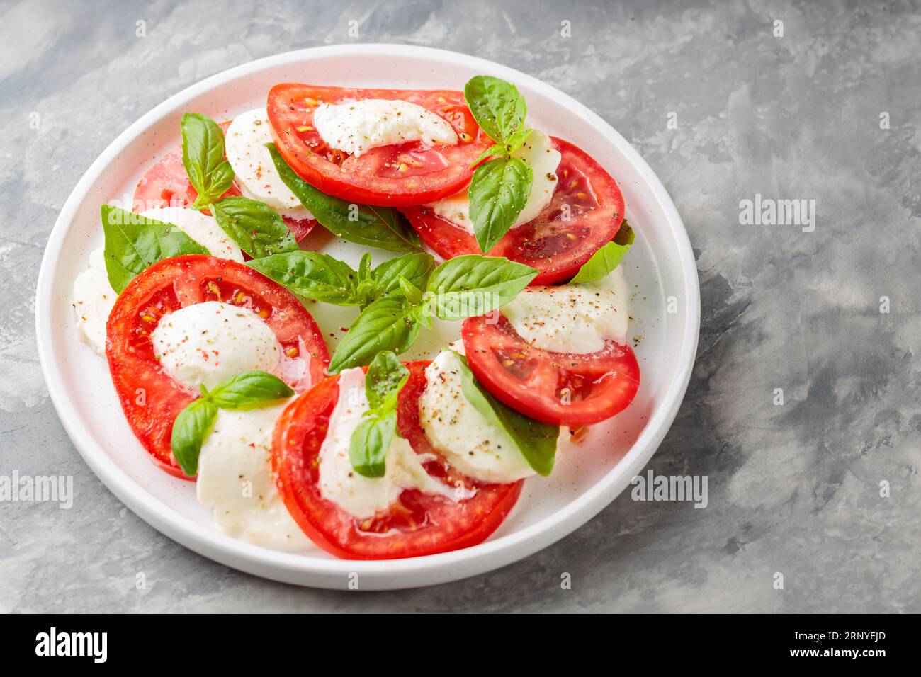 Delectable Caprese Salad on White Plate with Concrete Background. Top View. Copy Space Stock Photo