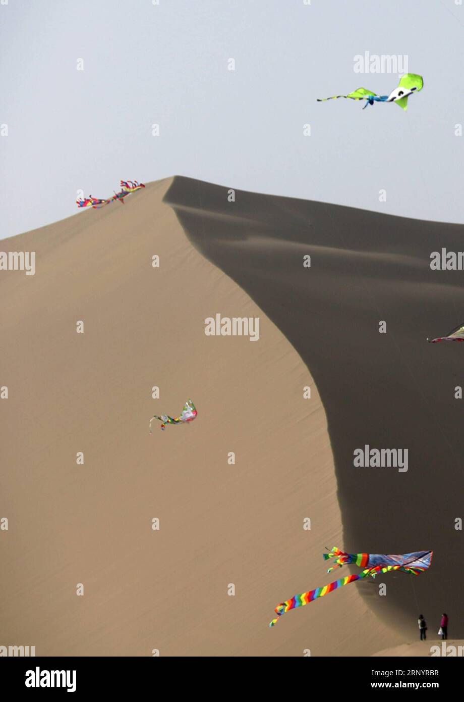 (180331) -- DUNHUANG, March 31, 2018 -- People fly kites at the scenic spot of the Crescent Spring, a crescent-shaped lake surrounded by deserts at the foot of the Mingsha Hill, in Dunhuang, northwest China s Gansu province, March 31, 2018. ) (dhf) CHINA-GANSU-DUNHUANG-KITE (CN) ZhangxXiaoliang PUBLICATIONxNOTxINxCHN Stock Photo